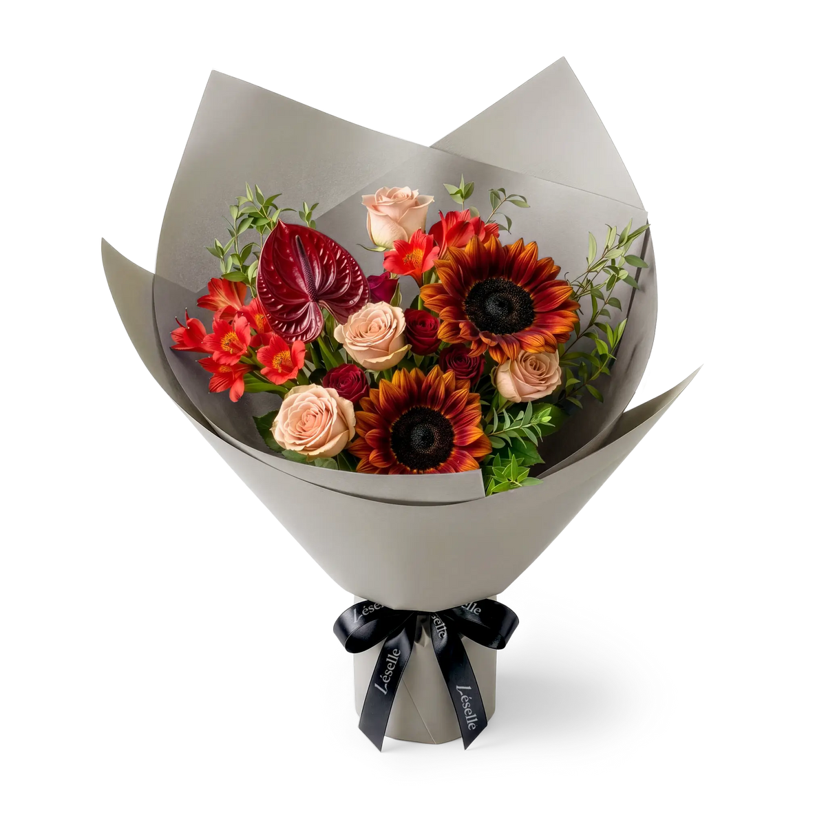 A wrapped flower bouquet featuring burgundy sunflowers, cappuccino roses, a dark red anthurium, and green foliage, wrapped in a grey paper sleeve with a black ribbon, on a transparent background.
